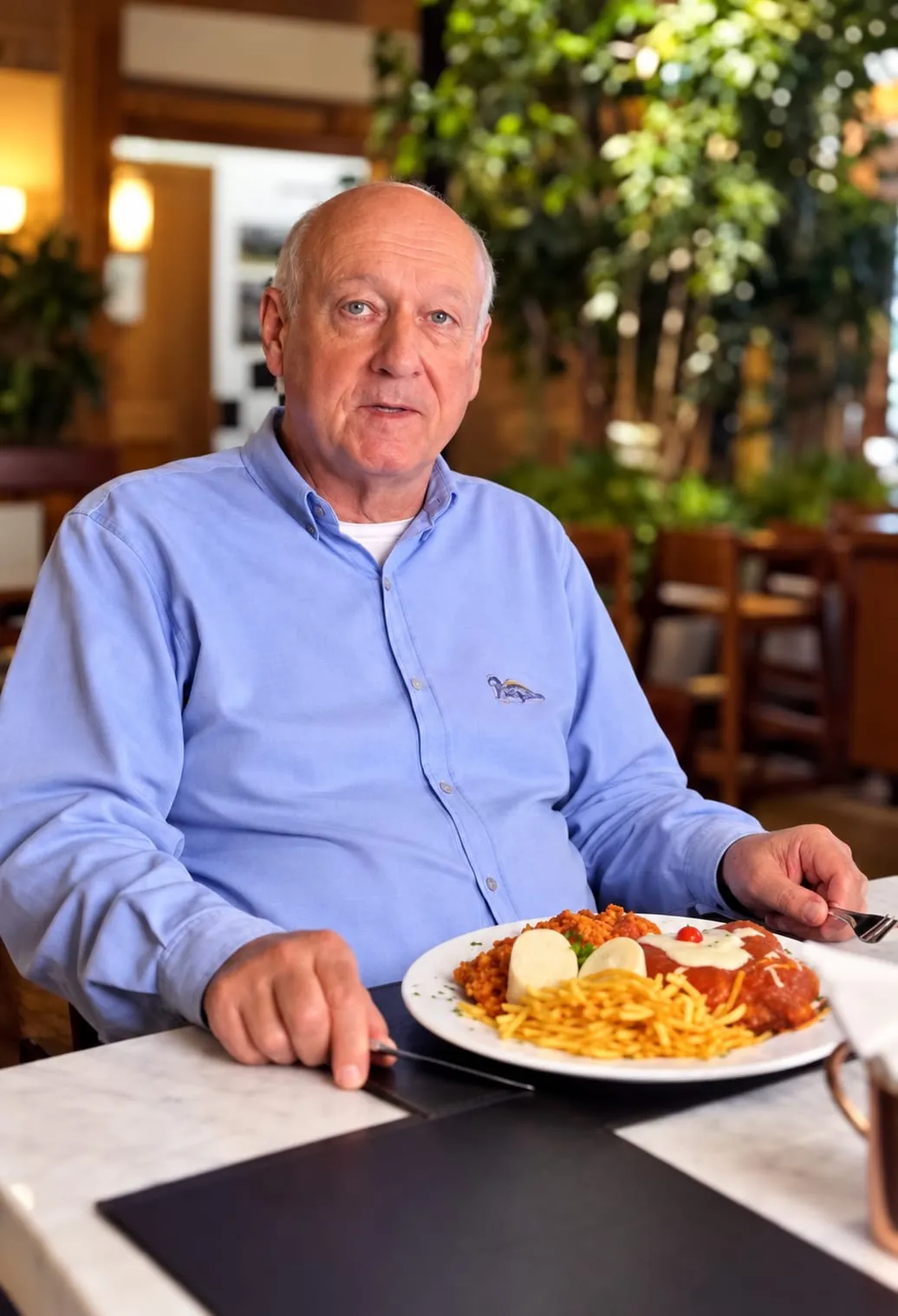Almoço servido no salão claro, com mesa de mármore e plantas ao fundo