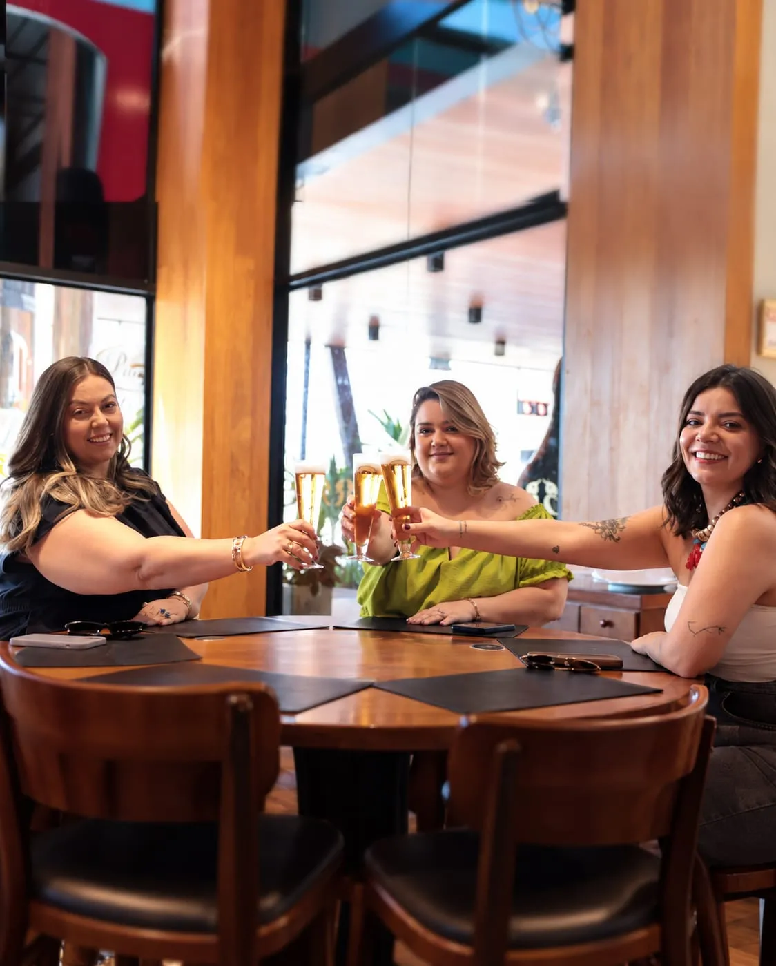 Grupo de amigas brindando à mesa no salão da Choperia Pinguim
