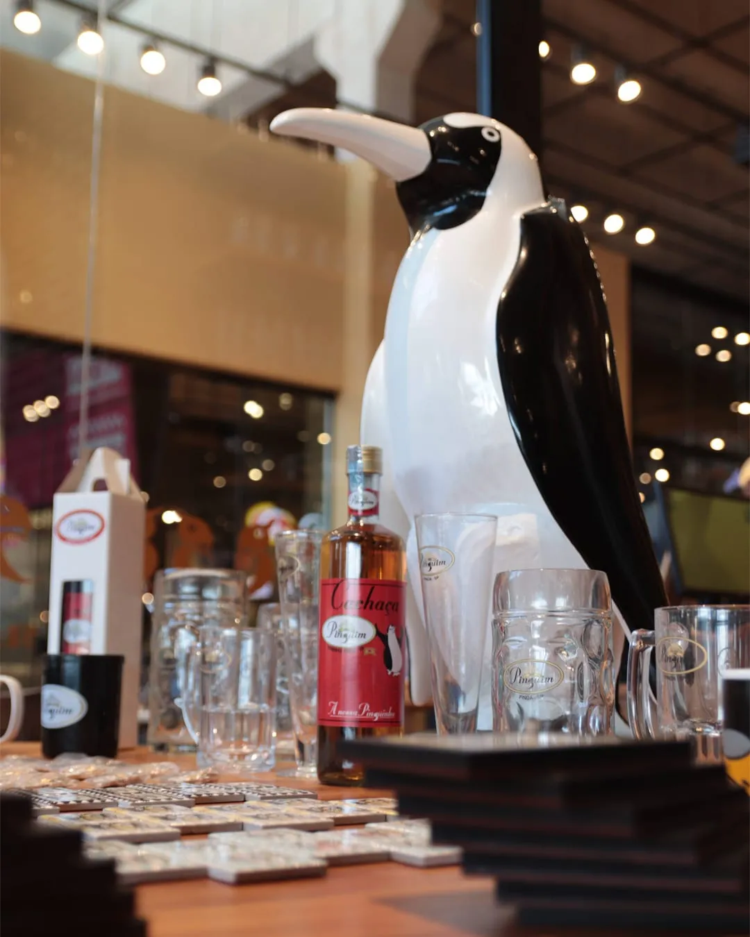 Pinguim de porcelana gigante sobre o balcão, entre taças e canecas
